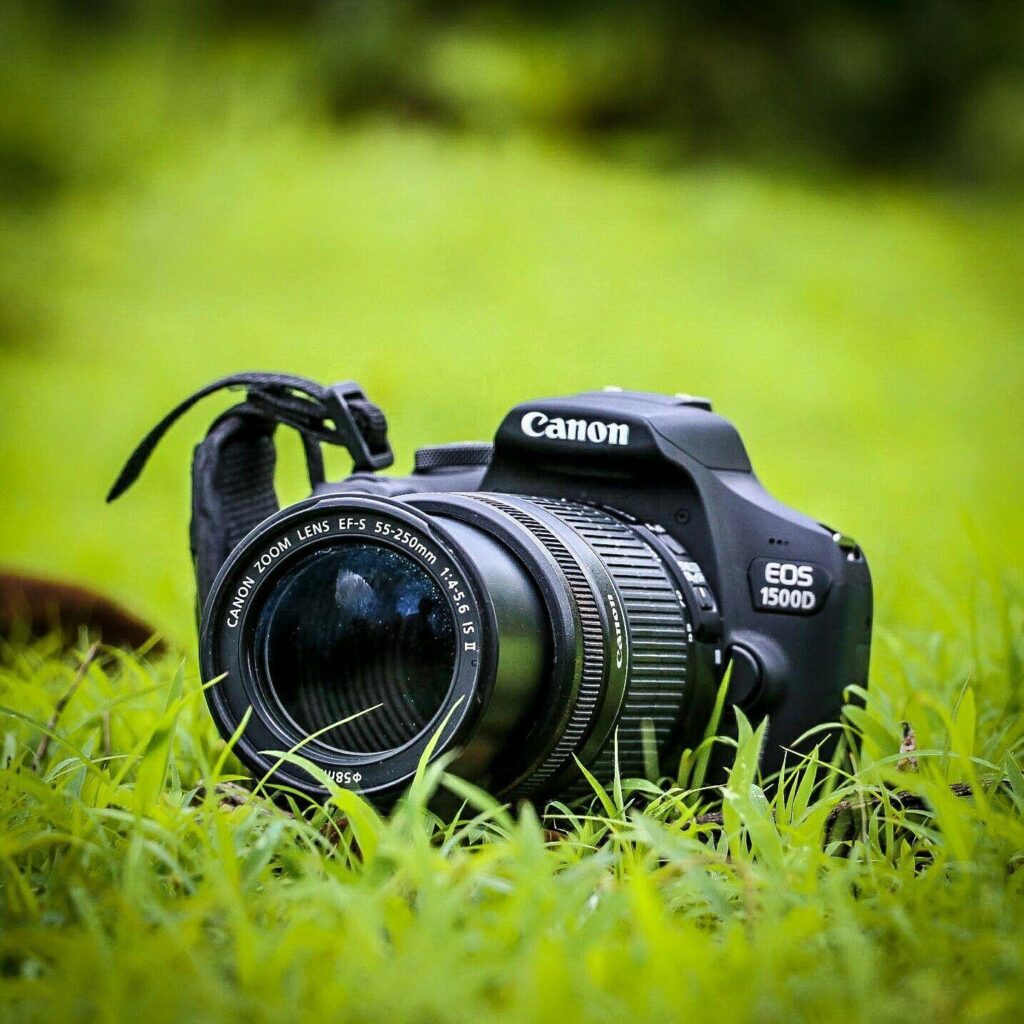 “Canon EOS 1500D DSLR camera with 55-250mm zoom lens placed on green grass, representing professional wedding photography equipment used by top wedding photographers in Hyderabad.”