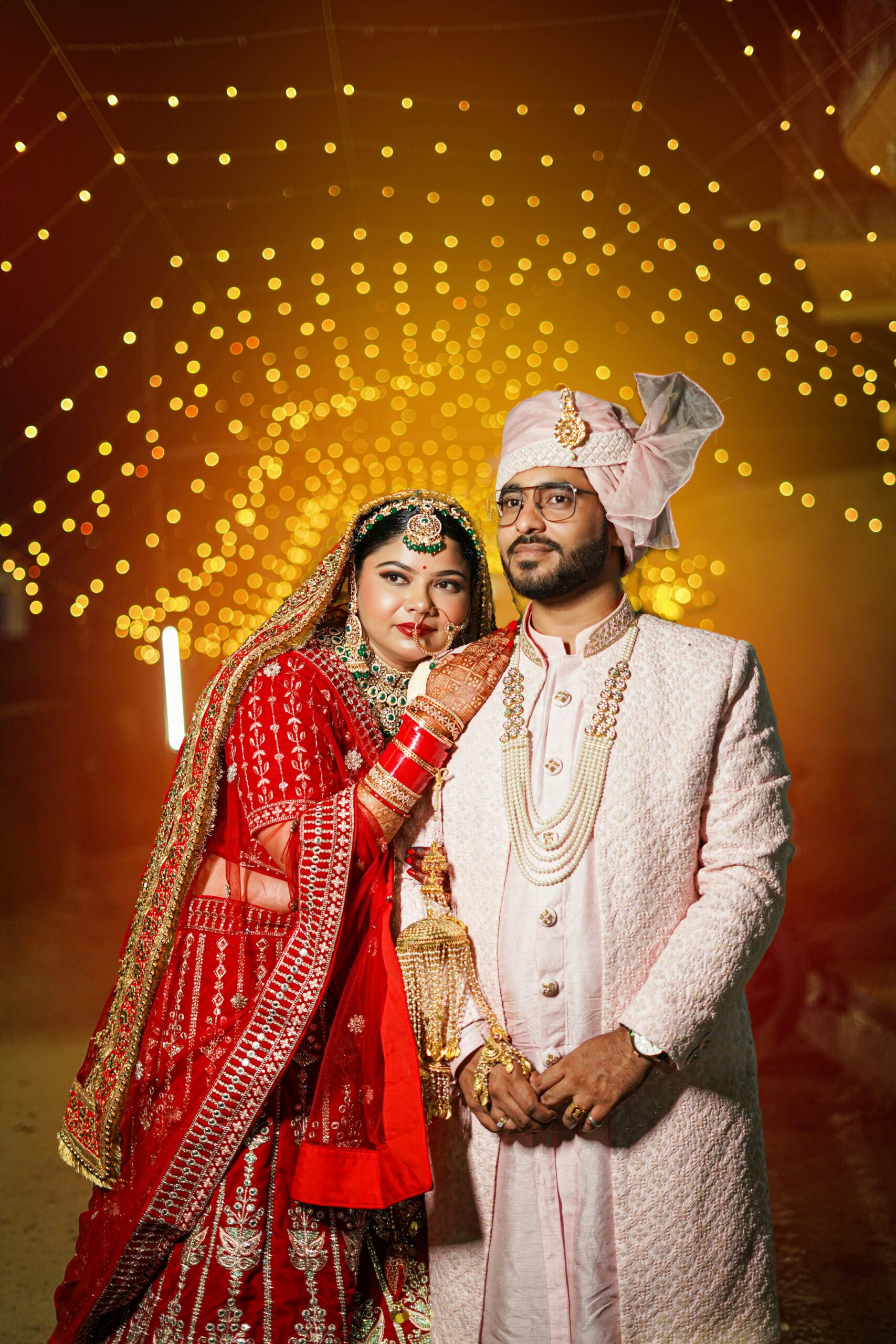 alt="Indian wedding couple posing in elegant attire under golden lights in Hyderabad"